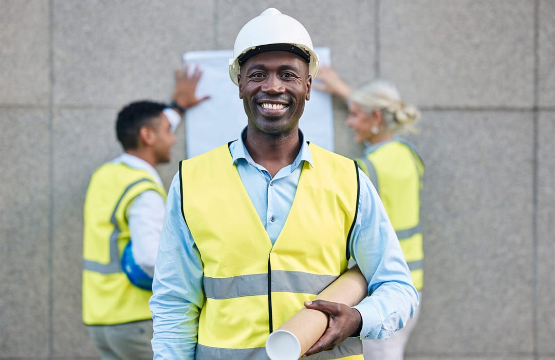 Smiling site engineer in hard hat and safety vest at a construction project in Kenya